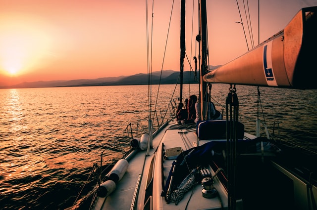 Fotografía de una embarcación de recreo con dos personas a abordo en el mar y al atardecer