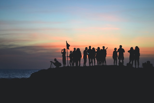 Fotografía de un grupo de personas en la cima de una montaña al atardecer